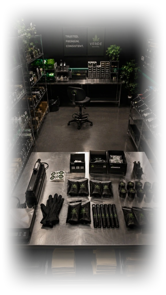A cannabis inventory and packaging prep room with wire shelving, gloves, and labeled product on a steel table